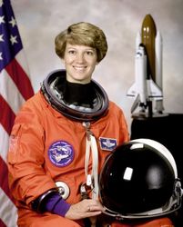 Portrait of Eileen M Collins shown wearing orange Launch and Entry Suit with helmet