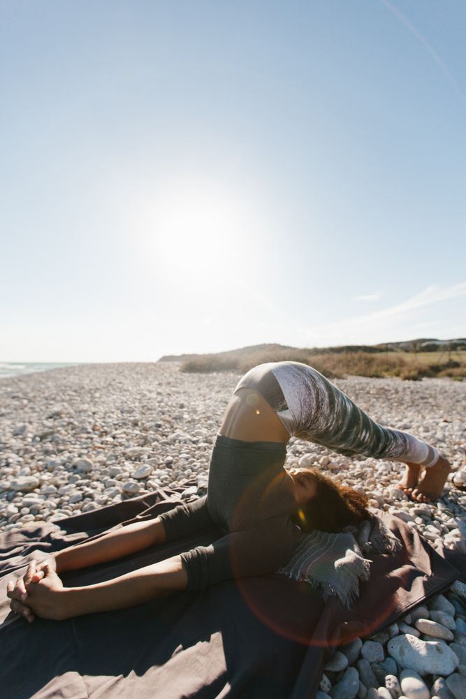 Sportive woman performing yoga posture in the beach