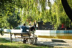 Man with stroller sitting on bench in city park