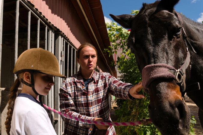 Instructor points to horse while girl holds lead rope.