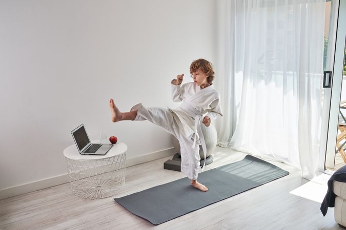 Barefoot boy practicing kicks a home