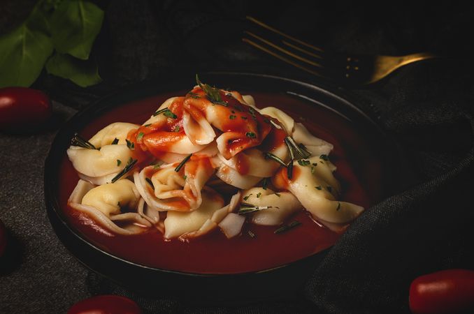 Plate of delicious ravioli with tomato sauce served on table