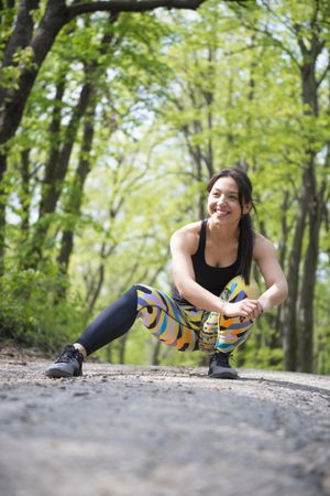 Smiling woman stretching her legs in colorful leggings