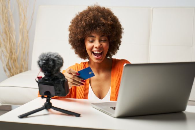 young latina woman with afro hair happy to shop online with laptop and pay by credit card