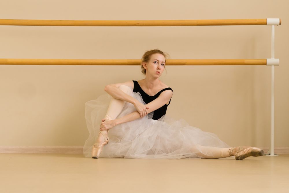 Ballet dancer sits elegantly on the studio floor