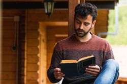 Pensive man chilling on terrace with book