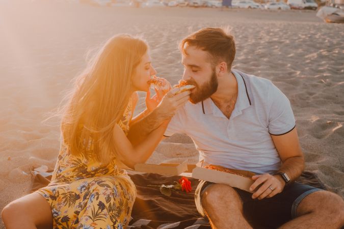 Lovely couple eating together at sandy beach