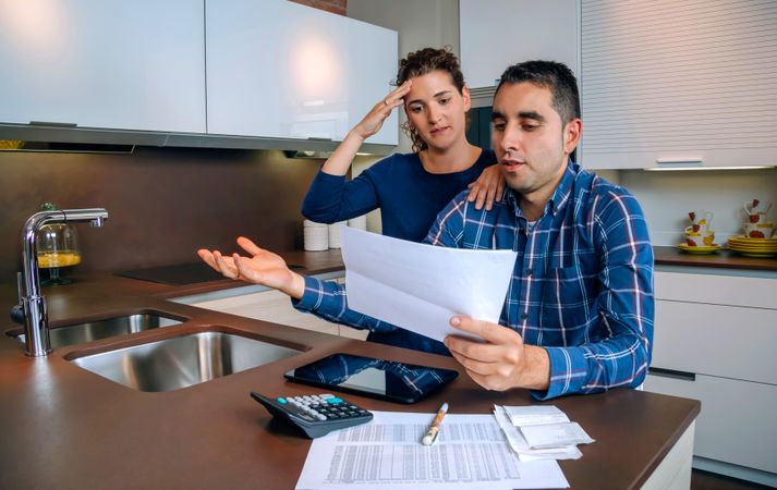 Tense couple reviewing their bills together in the kitchen