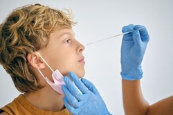 Crop nurse taking coronavirus test from boy in clinic