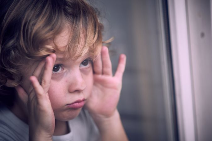 Cute boy looking out window at home