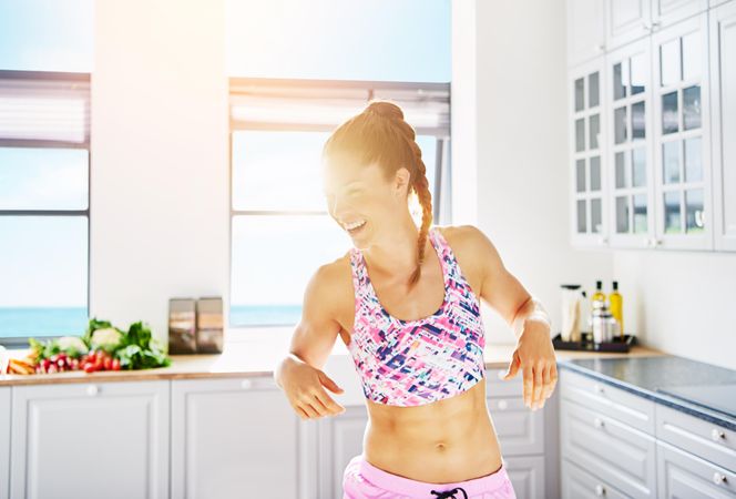 Smiling fit woman in sports gear in bright kitchen