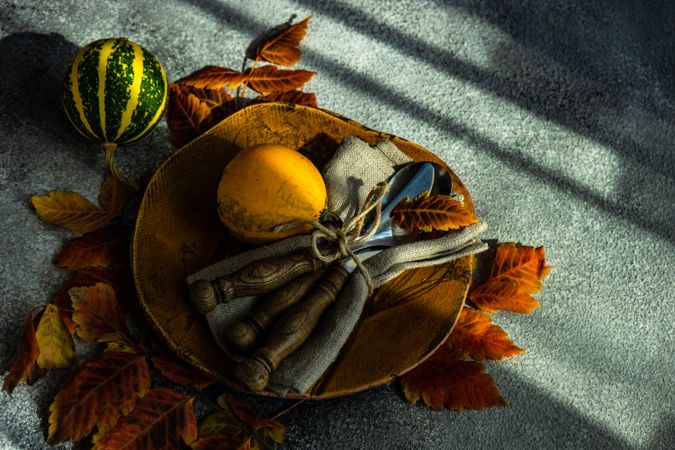 Fall table setting with yellow leaves and squash on stone background with shadow