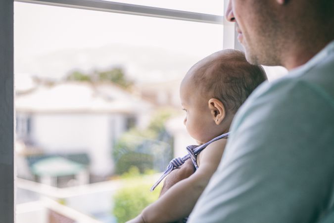 Father with baby looking out window