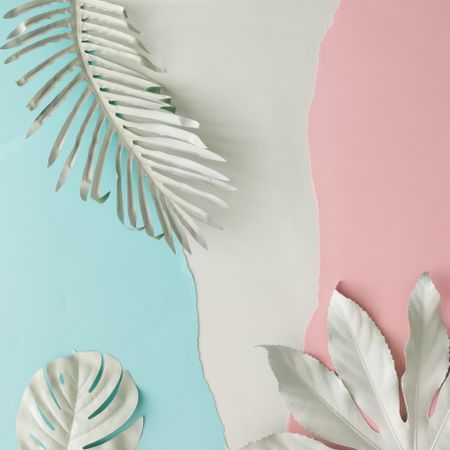 Pieces of ripped pastel colored paper in pattern with tropical leaves