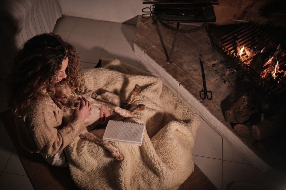 Woman with dog chilling near fireplace in room