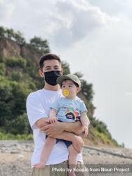 Man with facemask holding a baby 5zKoP4