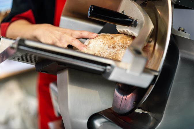 Close up of woman in butcher shop slicing meat