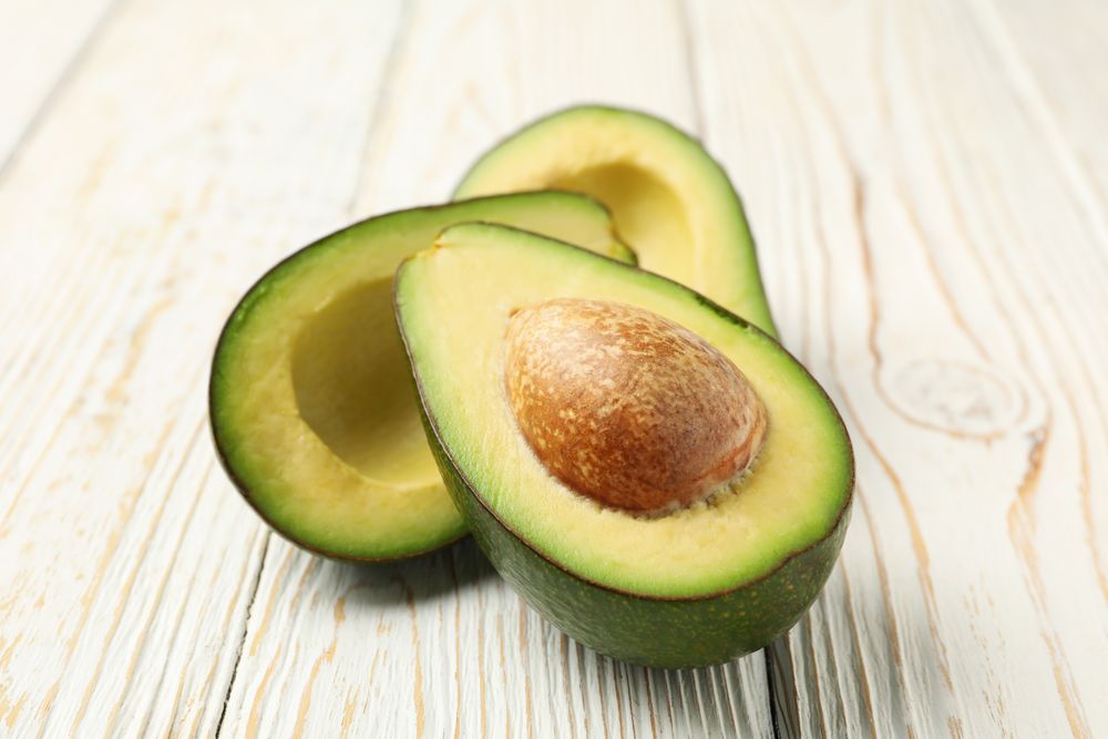 Ripe fresh avocado on plain wooden background, close up