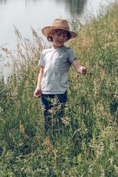 Cheerful boy playing with grass near river