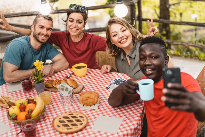 Group of friends relaxing taking selfie at picnic table