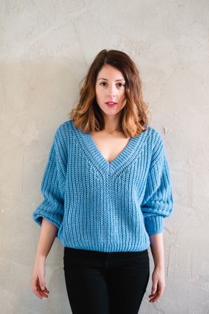 Charming woman in sweater near wall