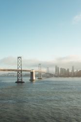 Long bridge construction over wavy water to city