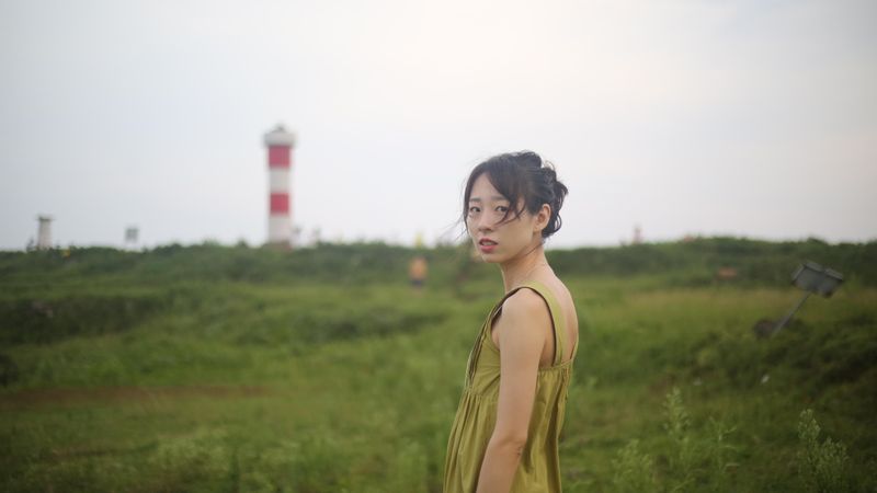 Woman in yellow top standing on green grass field