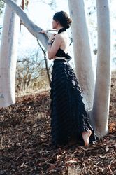 Woman with brunette hair bun reaches toward her chest while looking out in the woods