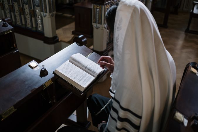 Jewish man wearing tallit reading the Holy Book in the synagogue