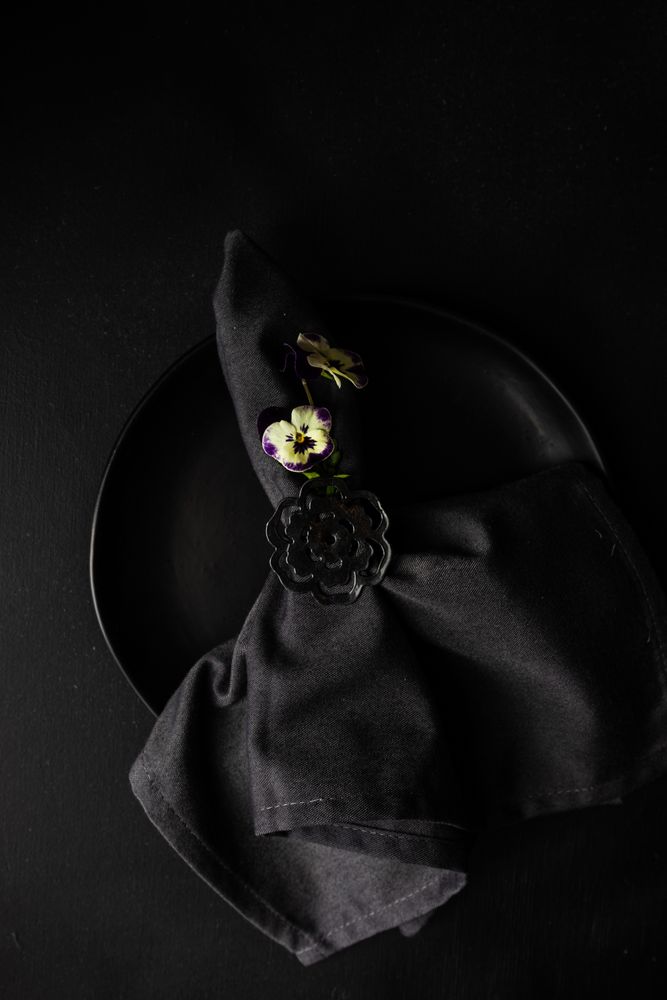 Close up of dark napkin on dark plate with delicate flower