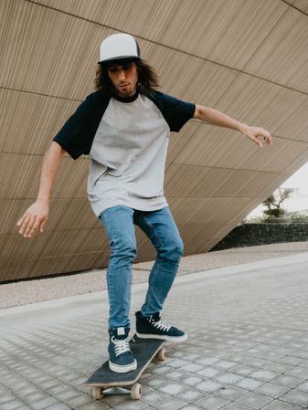 Sportive man riding skate on road along sloping wall