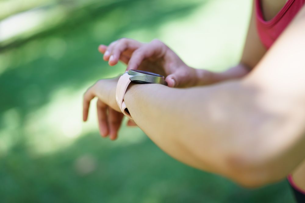 Exercising woman combines fitness with advanced technology, using a smartwatch to monitor her activities