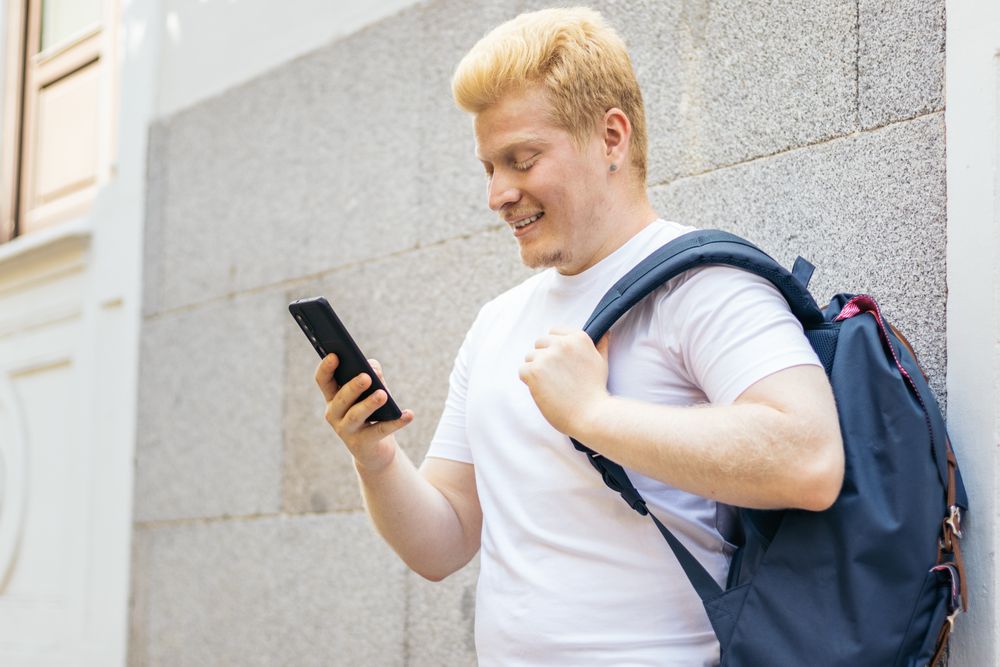 Latino man with albinism using smartphone in the city