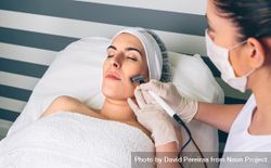 Woman receiving facial treatment on cheek in beauty center 432M9g