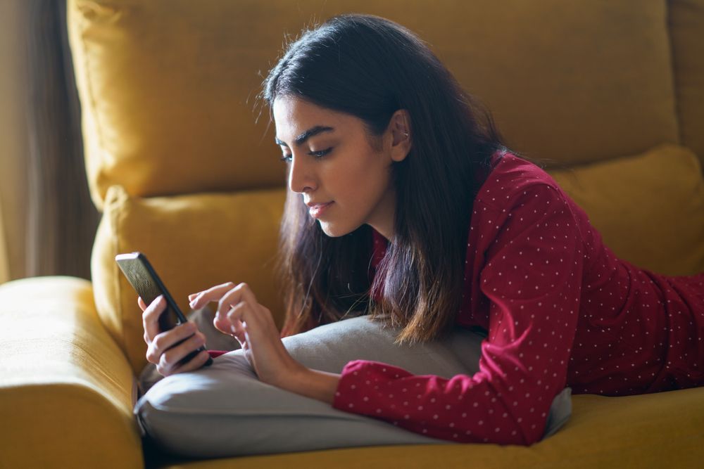 Woman relaxing at home while using a smart phone