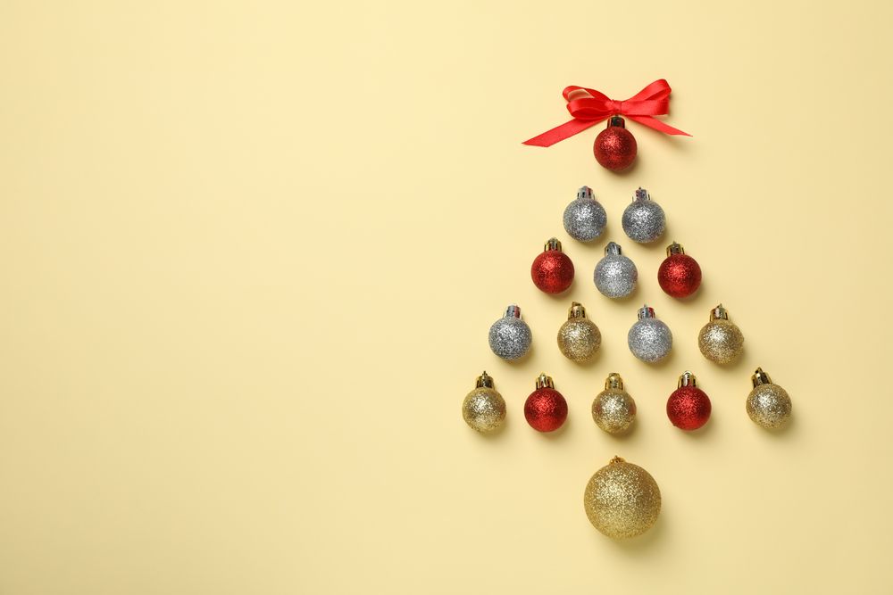 Christmas tree made of baubles on beige background, space for text