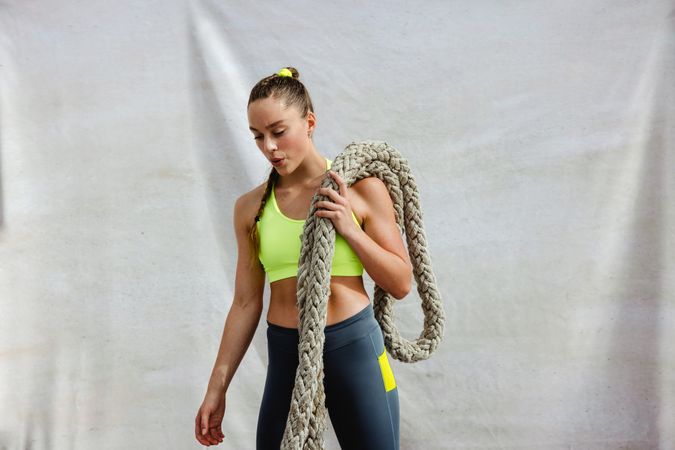 Female athlete doing HIIT workout using battle rope