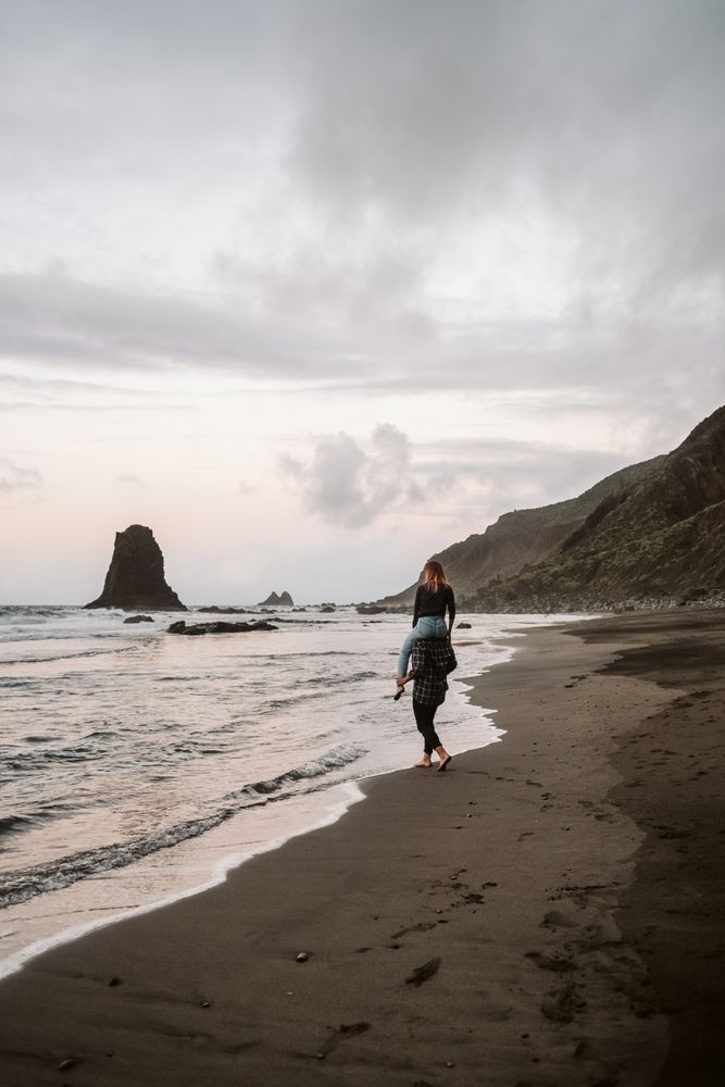 Unrecognizable man carrying woman on shoulders near sea