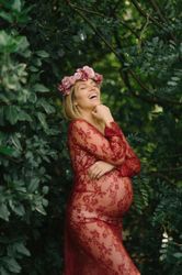 Pregnant woman with closed eyes touching belly and chin while standing in garden in sunny day