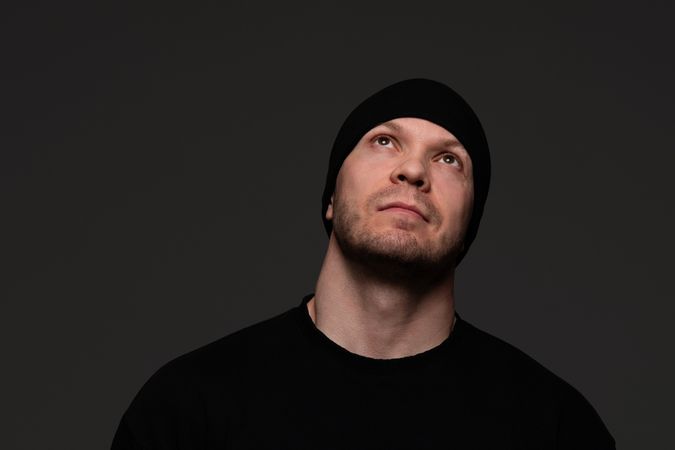 Man in beanie and sweatshirt looking up