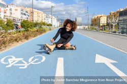 Smiling female in roller skates sitting in bike lane on nice day 0KqyM4