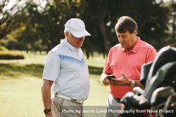 Older man taking break from golfing and using mobile phone 5alWv0
