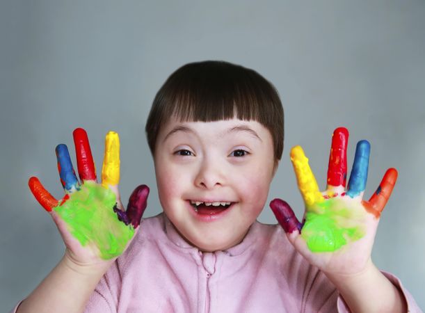 Portrait of young child with finger paints on palms of hand