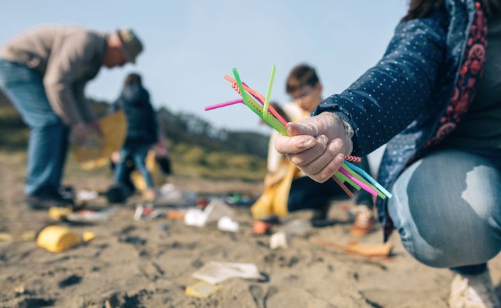 Woman showing handful of straws collected on the beach