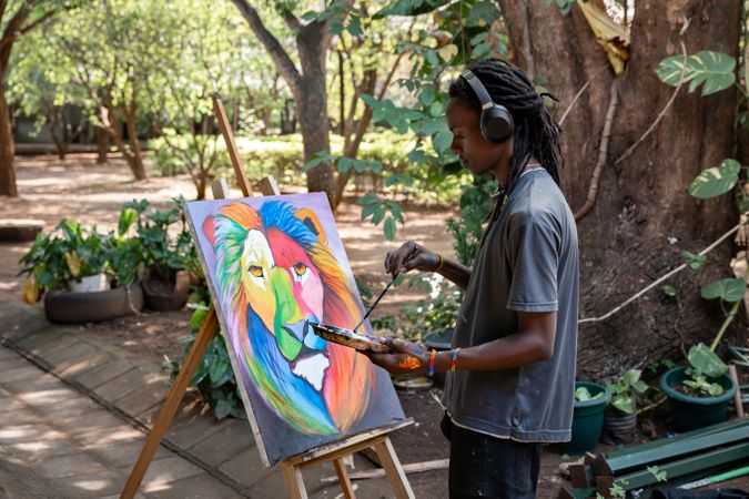 Black painter listening to music painting a picture outdoors