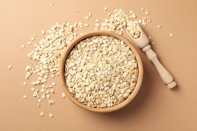 Bowl and scoop with oatmeal flakes on craft background