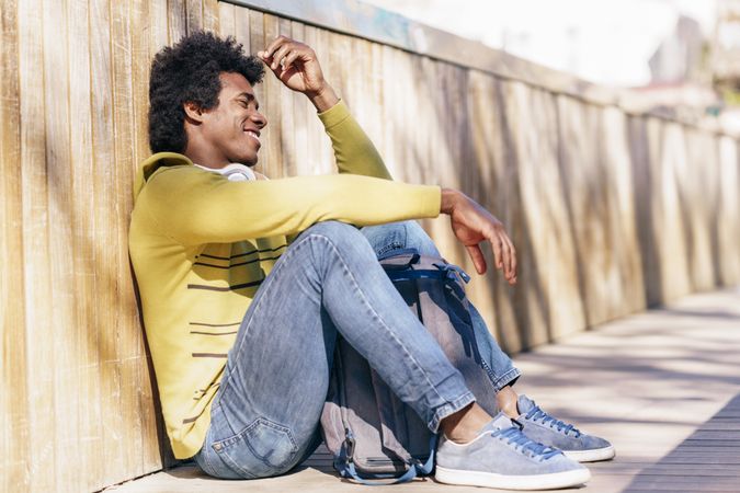 Man sitting against wall outside and smiling