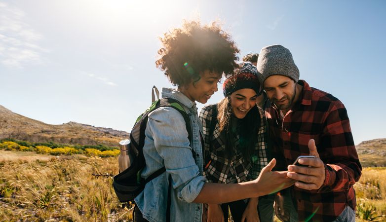 Group of young hikers looking at pictures on mobile phone