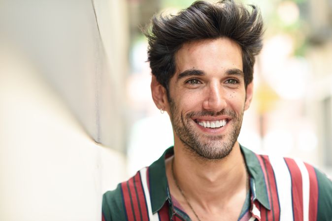 Portrait of man with dark hair smiling outside