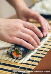 Hands of chef securing freshly made sushi rolls 4MQex4
